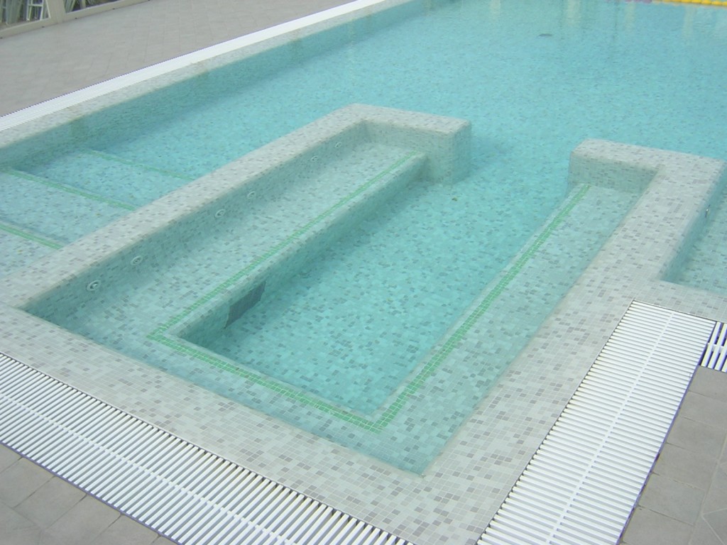 Piscina interrata in cemento armato e copertura in mosaico, con scale e seduta in acqua