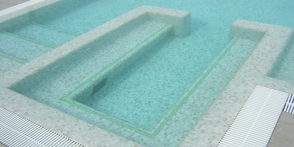 Piscina interrata in cemento armato e copertura in mosaico, con scale e seduta in acqua