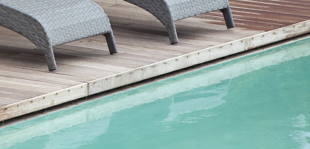 Piscina interrata esterna con bordo a sfioro nascosto Freedom e bordo in legno.