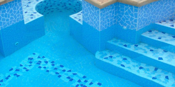 Piscina interrata con mosaico, scale e seduta.